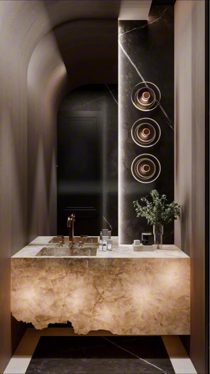 Dramatic luxury powder room with a dark stone feature wall and geometric tiled floor